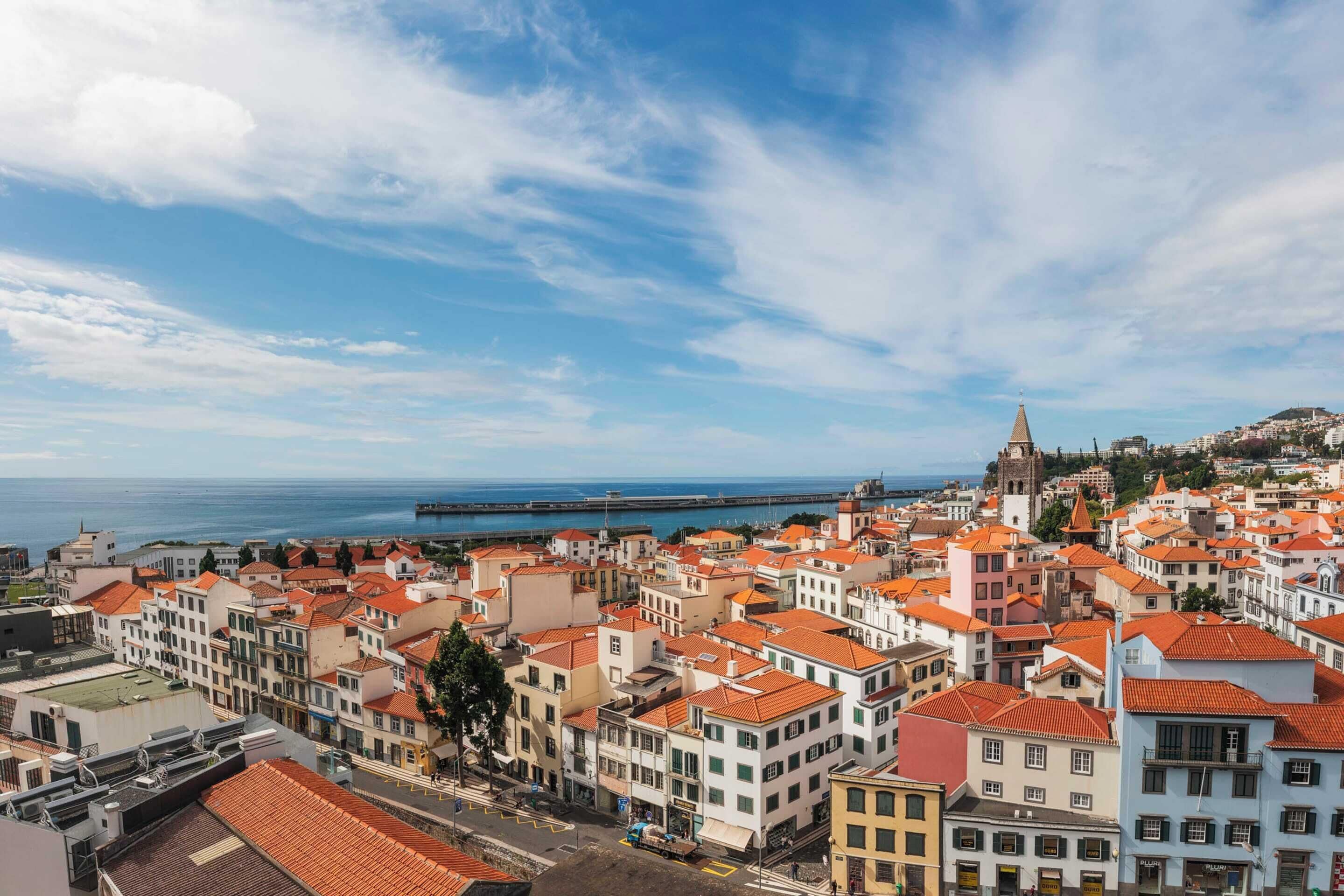 A coastal cityscape with historic buildings and a prominent tower.