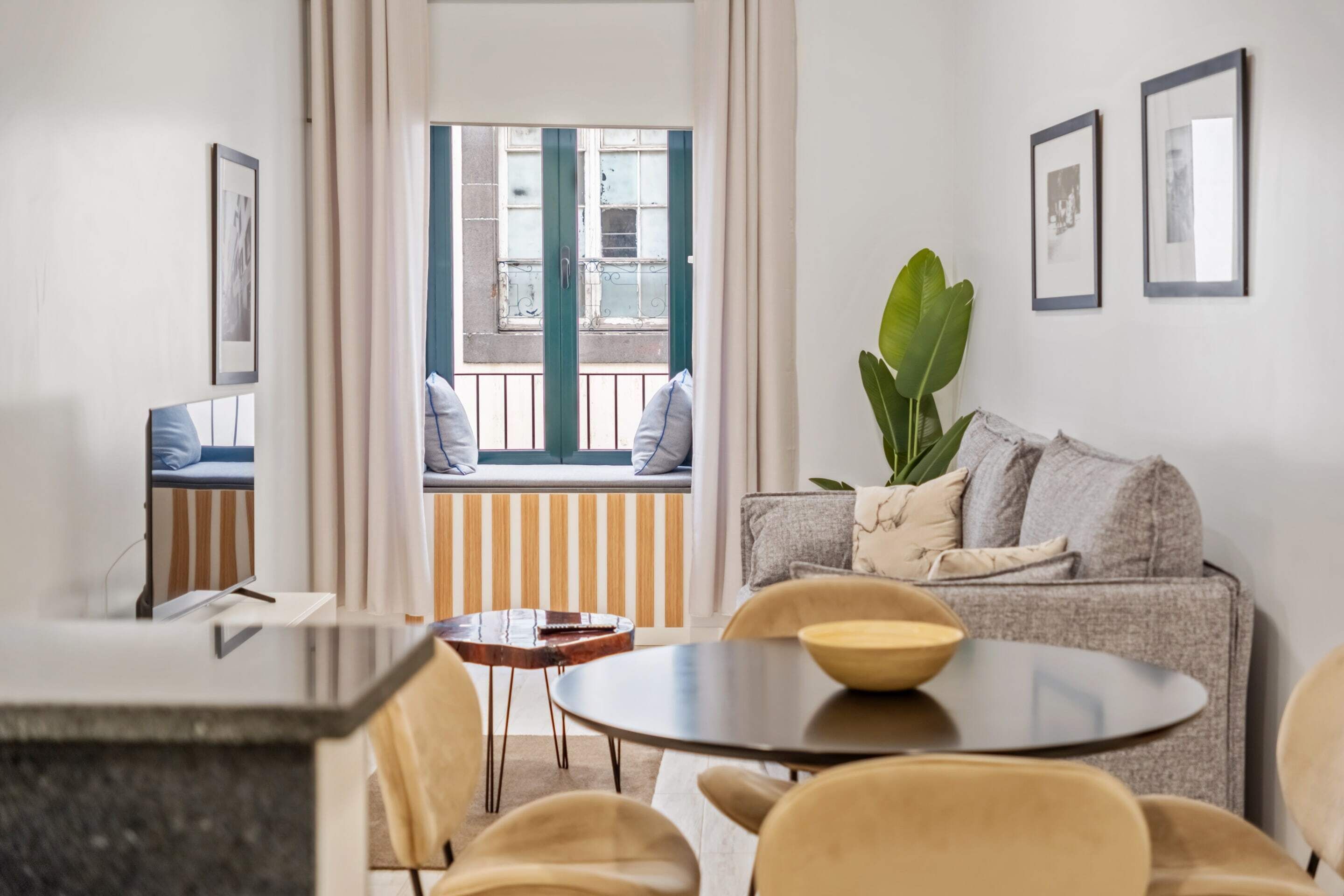 A modern living room with a sofa, a round table, and a view of a balcony.