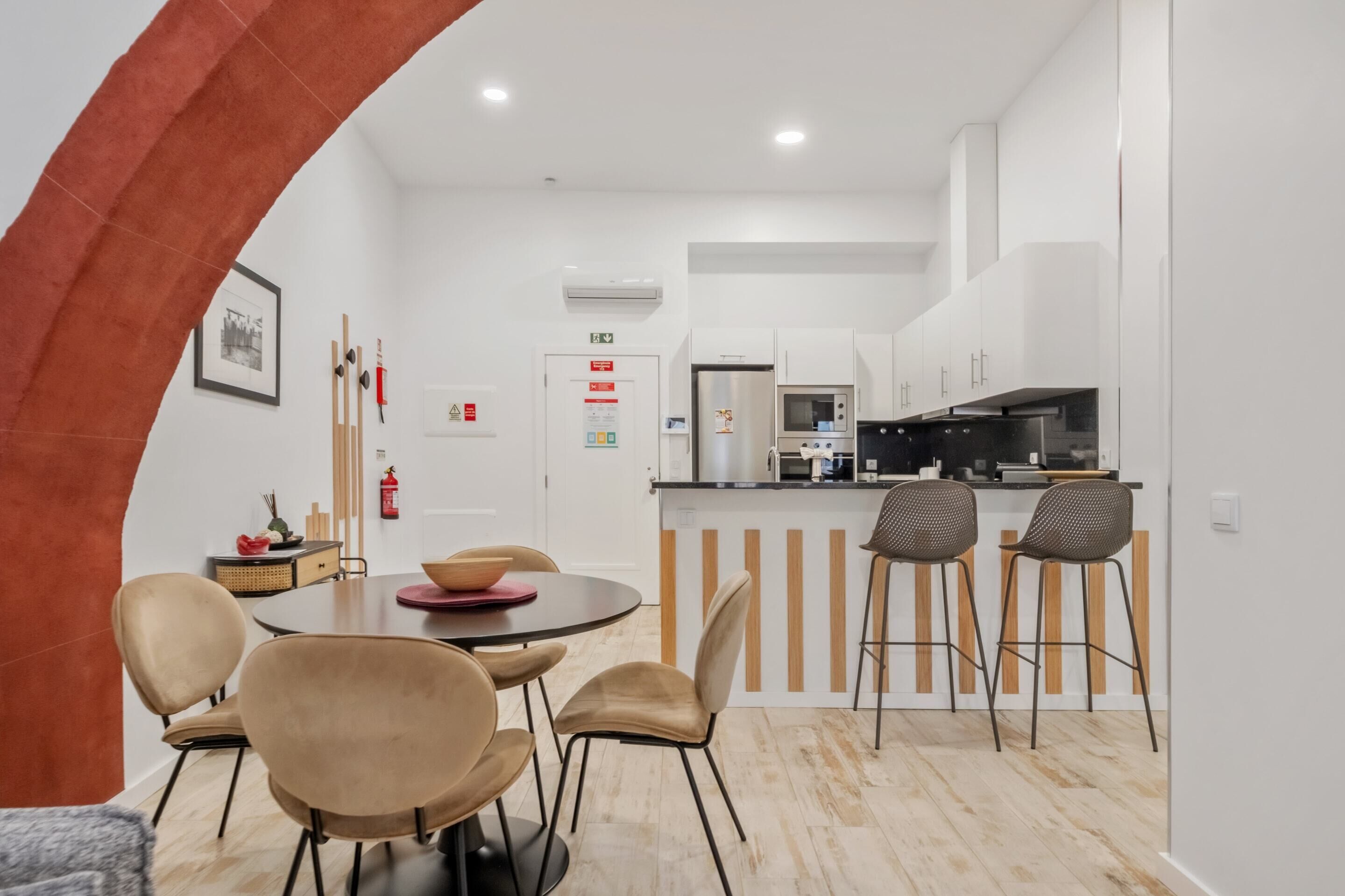 A modern kitchen with white cabinets, a stainless steel refrigerator, and a microwave. There is a dining area with a round table and four chairs.