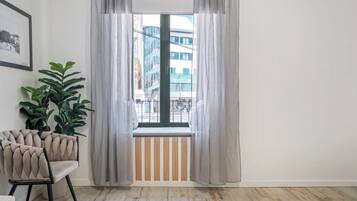 Een kamer met een raam, een kamerplant en een stoel.