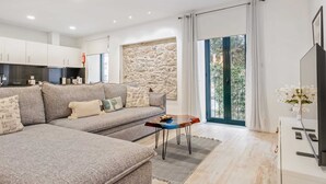 A modern living room with a sofa, coffee table, and a TV. - Tanoeiros Residence by An Island Apart (Funchal)