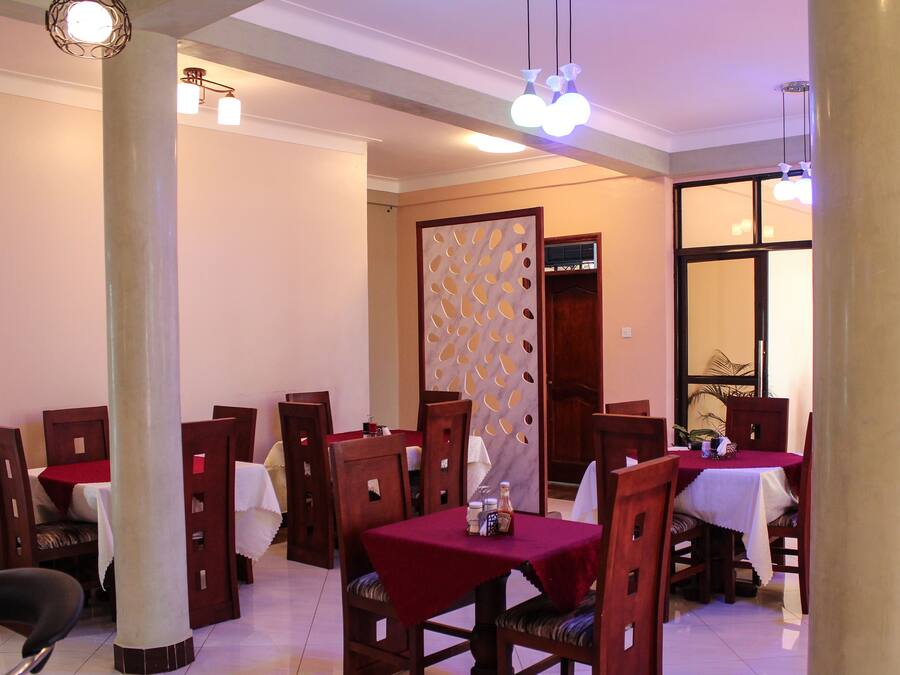 A dining area with multiple tables and chairs, a decorative partition, and hanging lights.