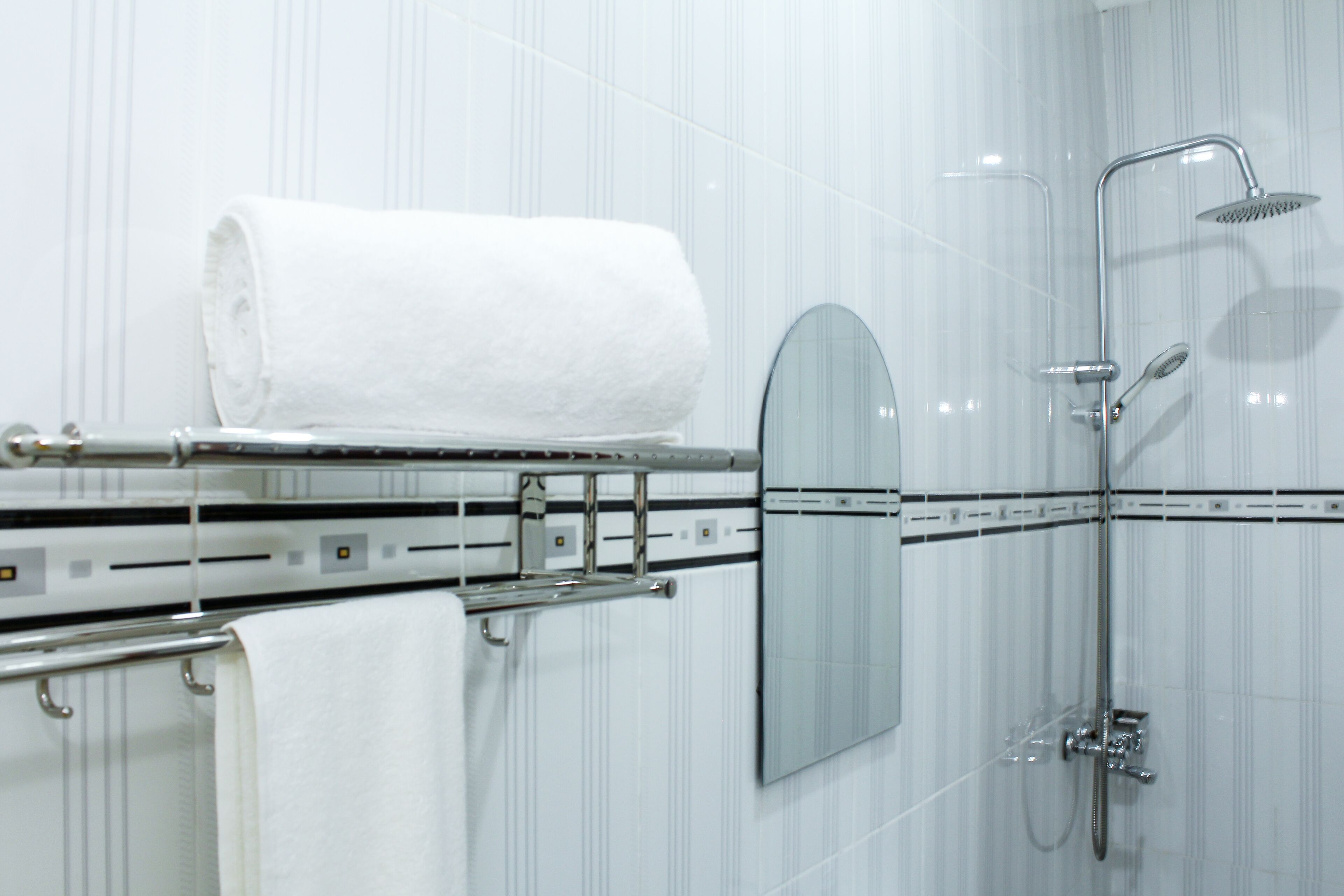 Une salle de bain moderne avec un porte-serviettes, une cabine de douche en verre et un miroir.
