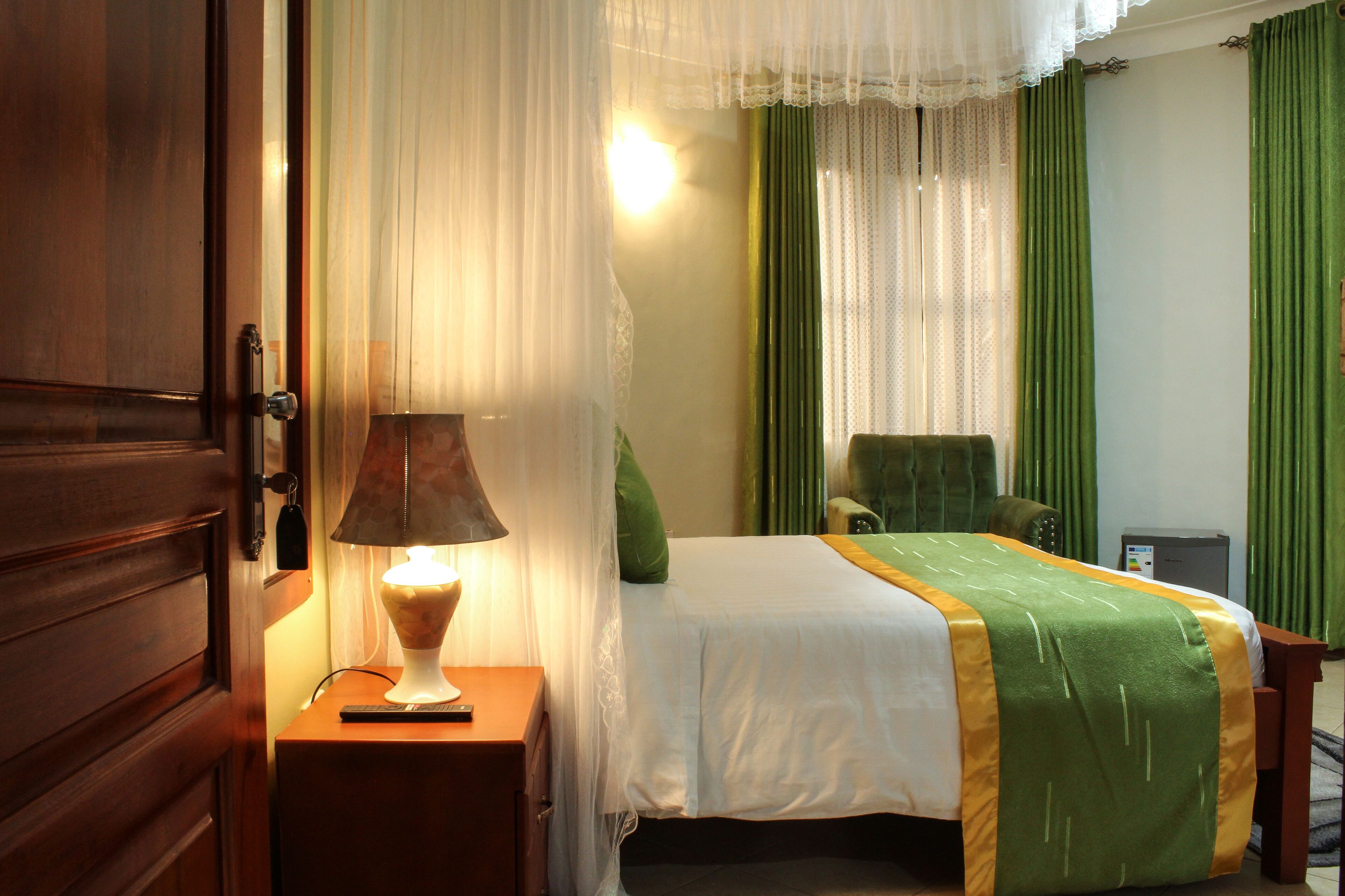 Una habitación de hotel con una cama, una mesita de noche con lámpara, una silla y un escritorio con ordenador.
