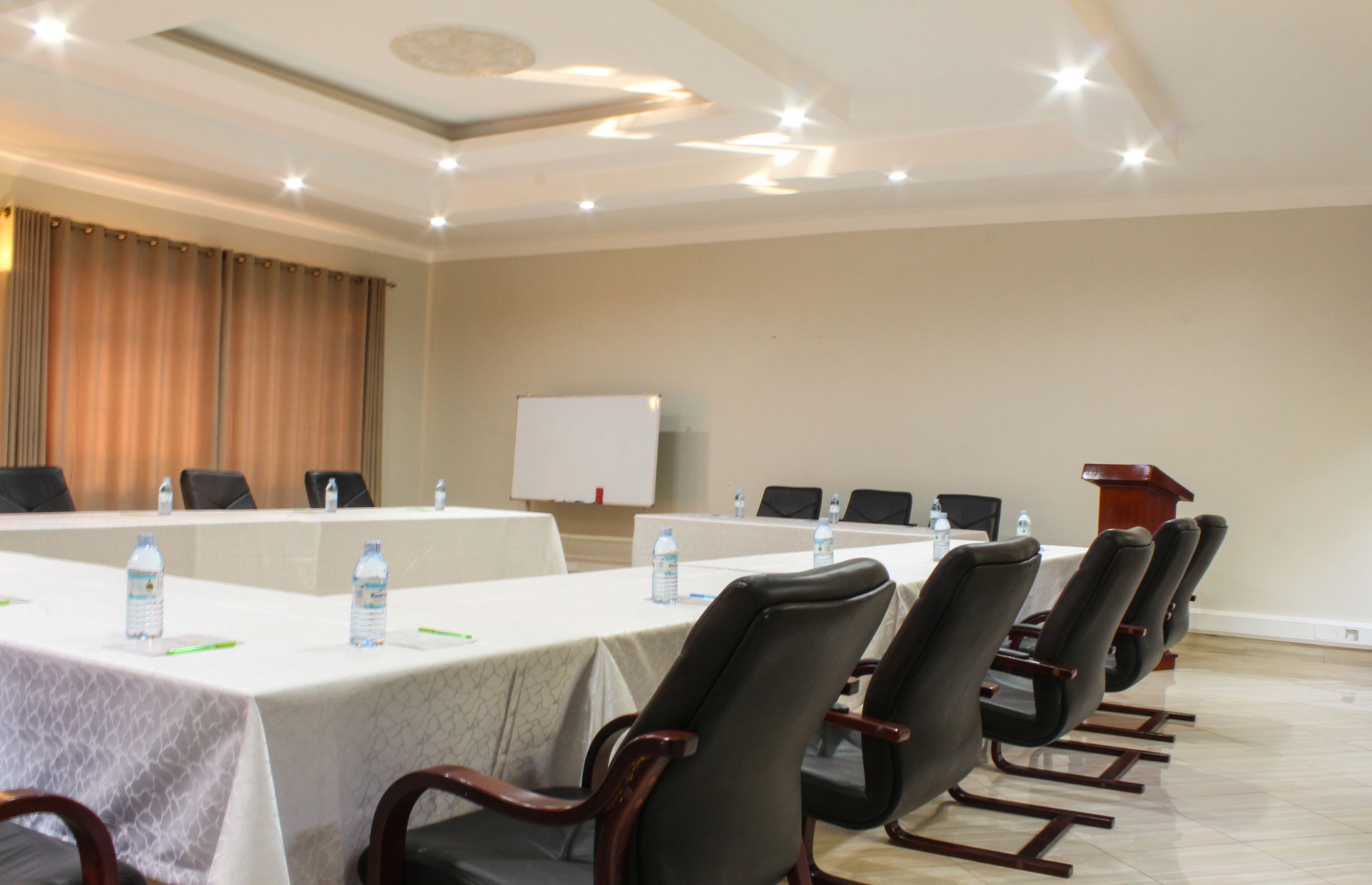 A conference room with a long table, chairs, water bottles, and a whiteboard.