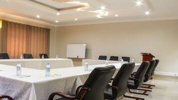 A conference room with a long table, chairs, water bottles, and a whiteboard.