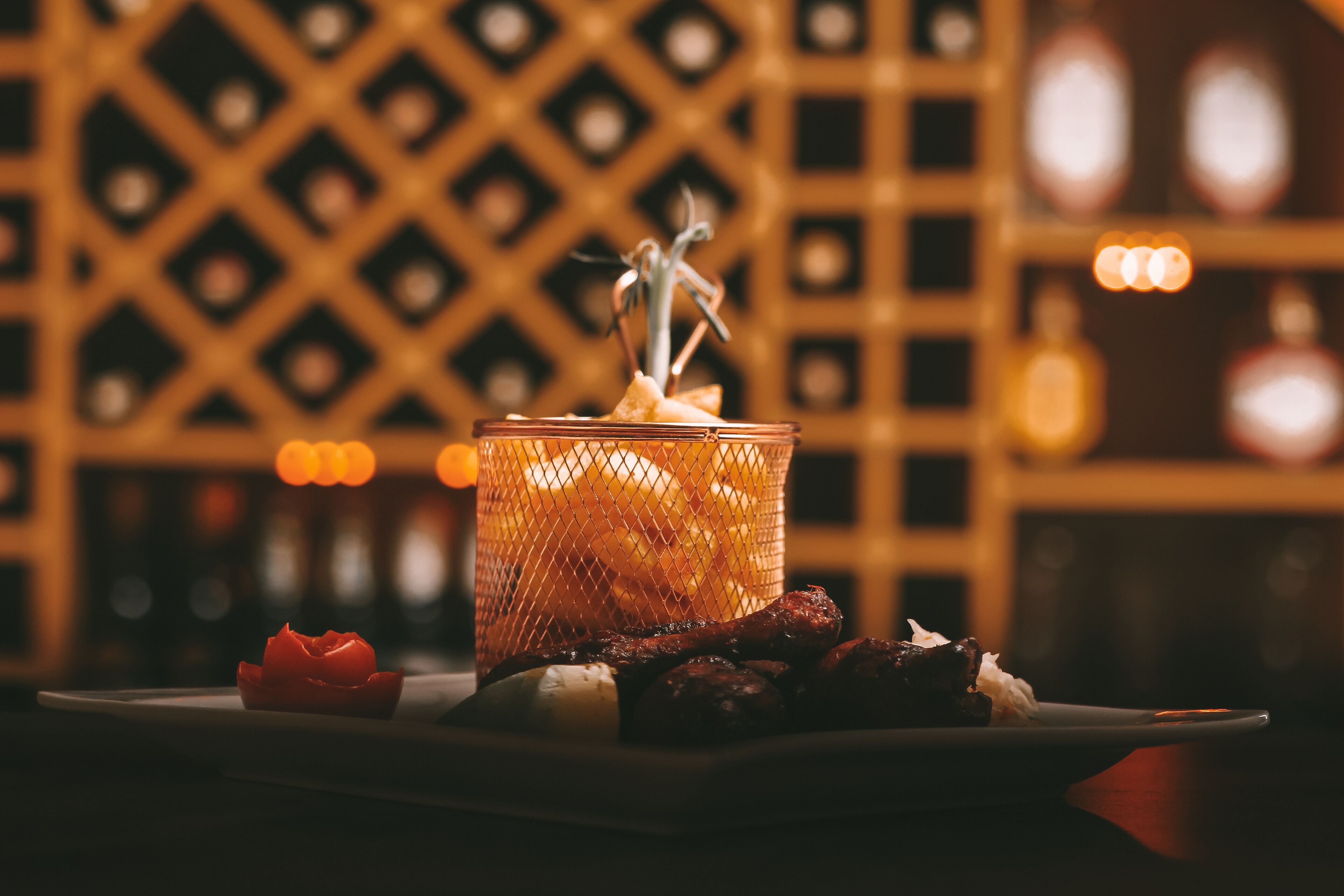 A candle in a glass holder on a table with a plate of food and a decorative item.