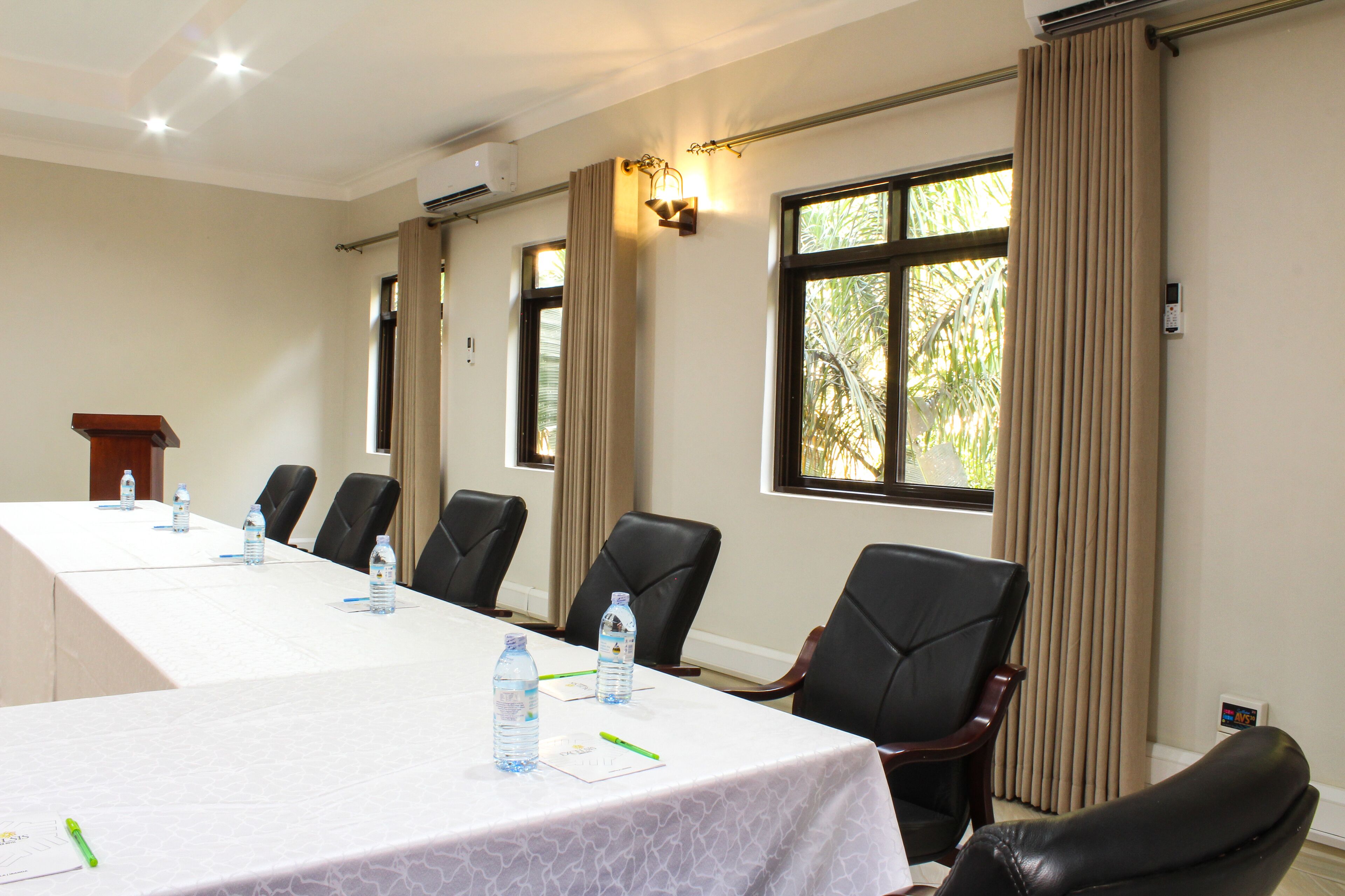 A conference room with a long table, chairs, water bottles, and a podium.