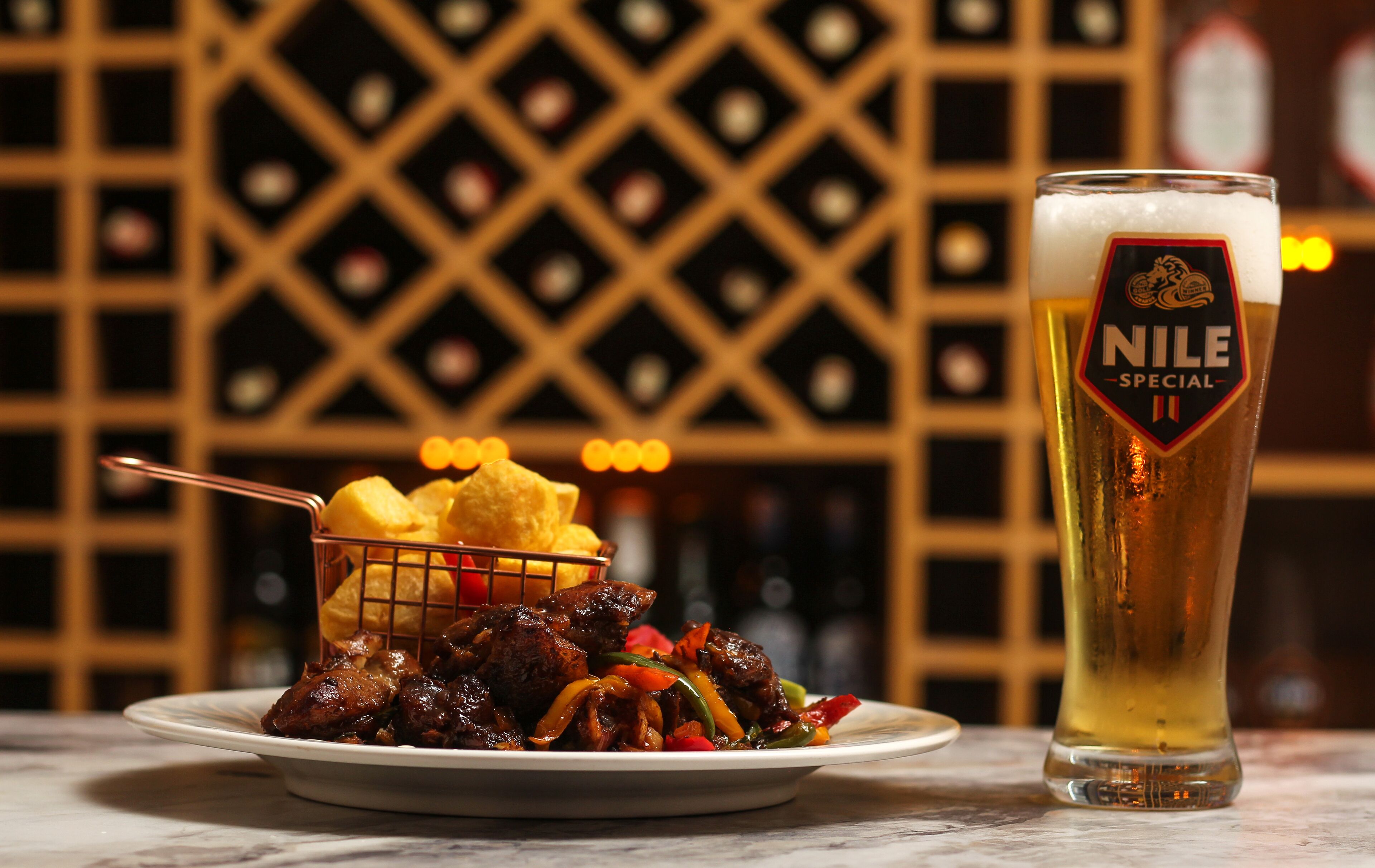 A plate of food and a glass of beer with a label reading "NILE SPECIAL" on a marble surface.