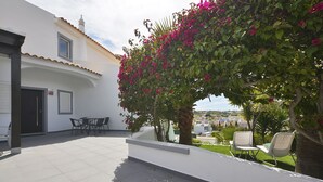 A courtyard with a white building, a palm tree, and a chair.