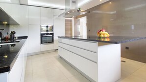 A modern kitchen with white cabinetry, a black countertop, and a central island.