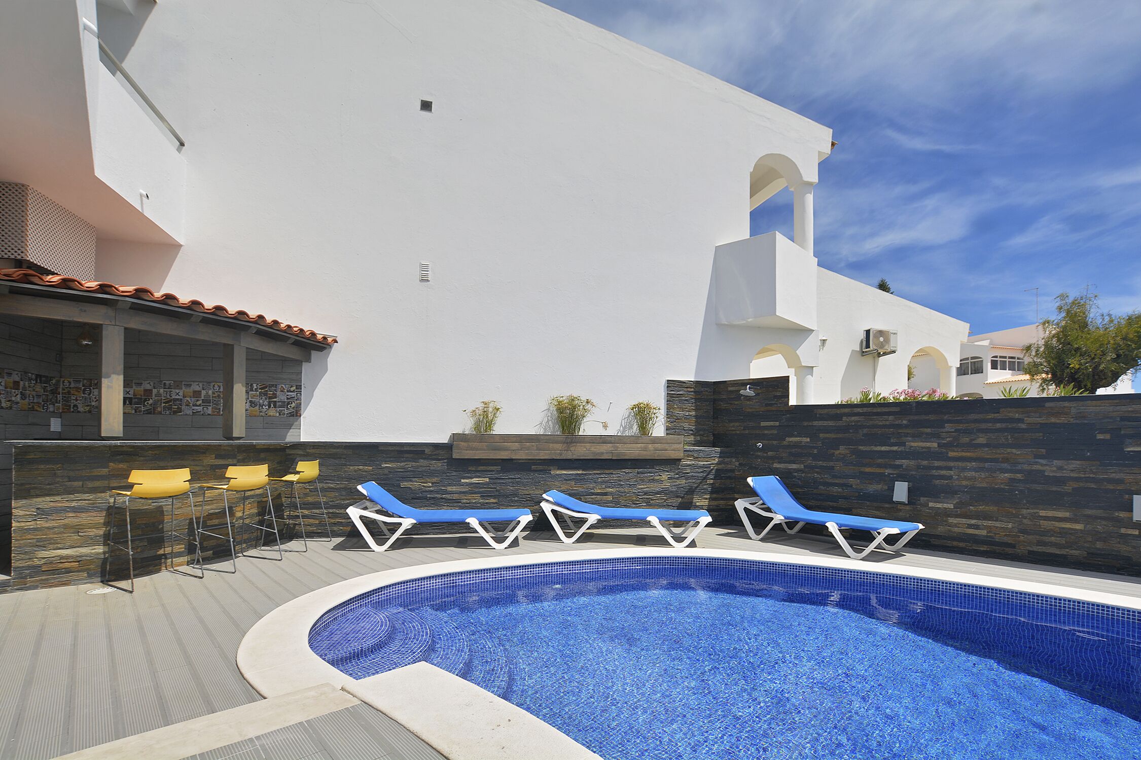 Une piscine avec des chaises longues et un espace bar.