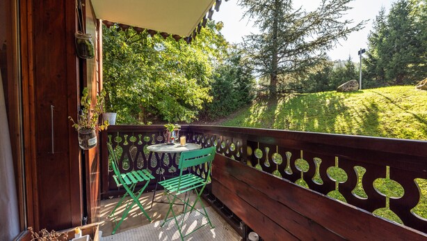 A wooden balcony with a table and chairs, surrounded by greenery and trees. - Wonderful apt 6 ppl with terrace (Morillon)