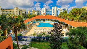 Ein Resort mit einem zentral gelegenen Pool, mehreren Lounges und dem Hintergrund von Hotelgebäuden.