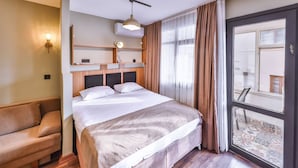 Habitación de hotel con cama, sofá, ventana con cortinas y vistas al exterior.