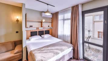 A hotel room with a bed, a sofa, a window with curtains, and a view of the outside.