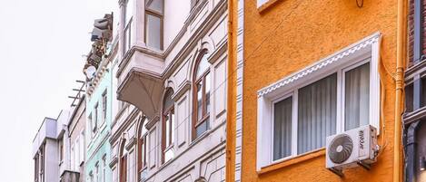 A street with multi-story buildings, some with balconies and air conditioning units.