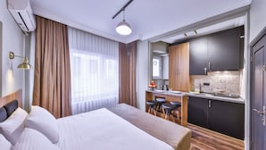 Una habitación de hotel con cama, escritorio y kitchenette.