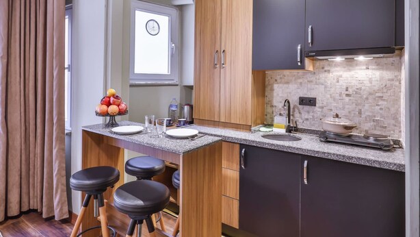 Una cocina moderna con una isla central, taburetes de bar y un horno empotrado.