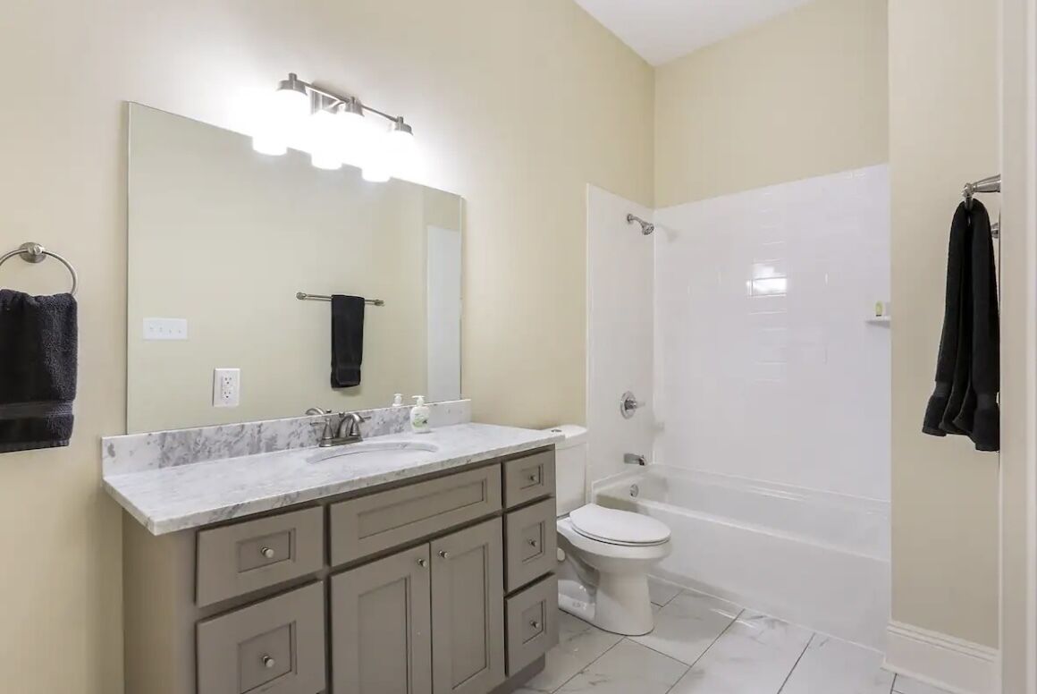 A bathroom with a sink, mirror, toilet, and bathtub.