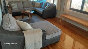 A modern living room with a sectional sofa, a round coffee table, and a bench. - Spacious 2 or 3 BR ocean side home with pool - private lot & panoramic views. (Utila)