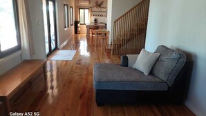 A spacious living area with a wooden floor, a grey sofa, and a dining area in the background. - Spacious 2 or 3 BR ocean side home with pool - private lot & panoramic views. (Utila)