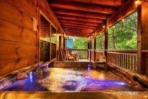 Puinen spa-alue, jossa on poreallas, puinen terassi ja näkymä metsään.