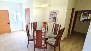 Un comedor con una mesa redonda y sillas, piso de madera y una puerta al fondo.