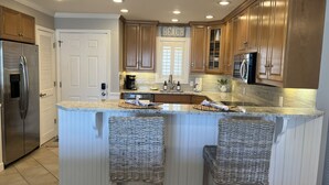 A kitchen with a central island, wooden cabinets, stainless steel appliances, and a sign that reads "BEACH".