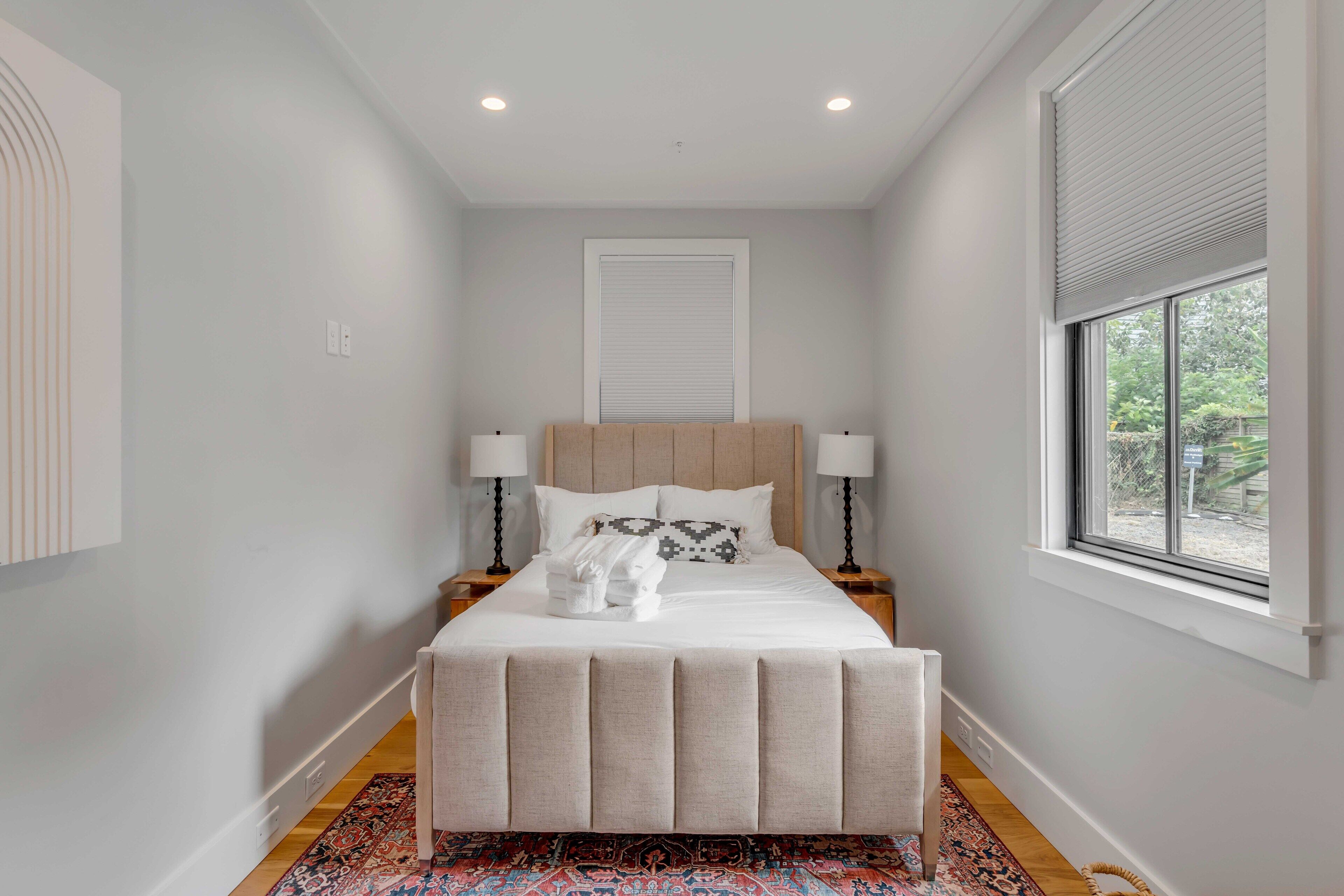 A bedroom with a bed, two bedside tables, a window, and a door.