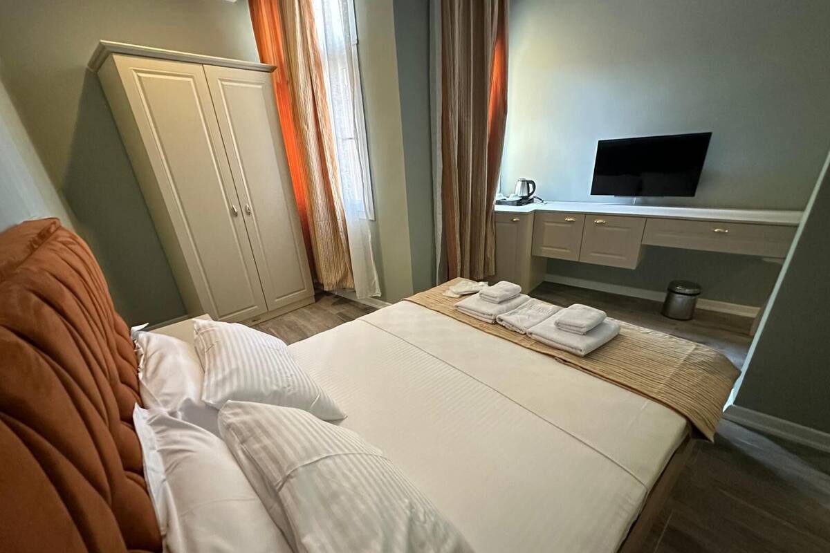 A hotel room with a bed, a desk, a television, and a wardrobe.