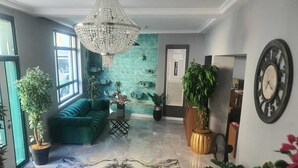 A modern living room with a teal sofa, a chandelier, and a marble floor. - St945 Palas Otel (Izmir)
