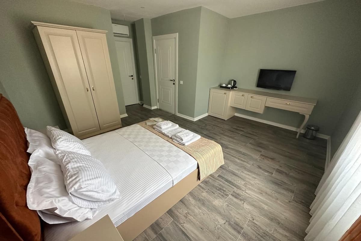 A bedroom with a bed, a desk, a television, and a wardrobe.