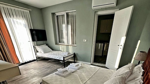 A hotel room with a large bed, a bedside table, a lamp, and a view of the kitchen. - St945 Palas Otel (Izmir)