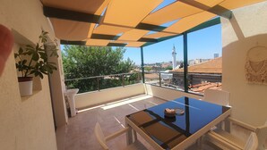 A balcony with a table and chairs, a potted plant, and a view of the cityscape. - St945 Palas Otel (Izmir)