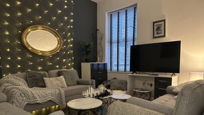 Un salon moderne avec un canapé, une table basse, un téléviseur et un miroir décoratif.