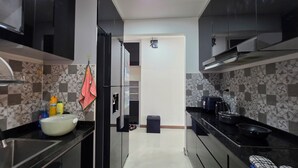 A modern kitchen with black cabinets, a stainless steel refrigerator, a sink, and a stove.