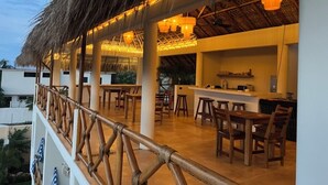 An outdoor dining area with thatched roof, wooden furniture, and ambient lighting.