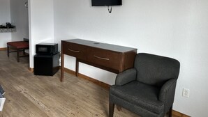 A room with a wooden desk, a chair, a television mounted on the wall, and a microwave on the floor. - Hochabel Hotel (Idabel)