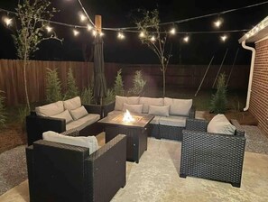 Una terrazza esterna con divanetti, un braciere e luci decorative.