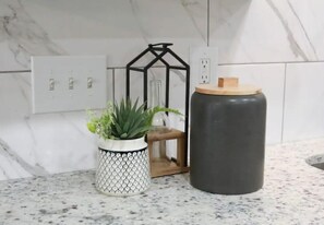 A kitchen counter with a patterned vase, a black metal lantern, and a cylindrical container. - SunChaser 042 (Brandon)