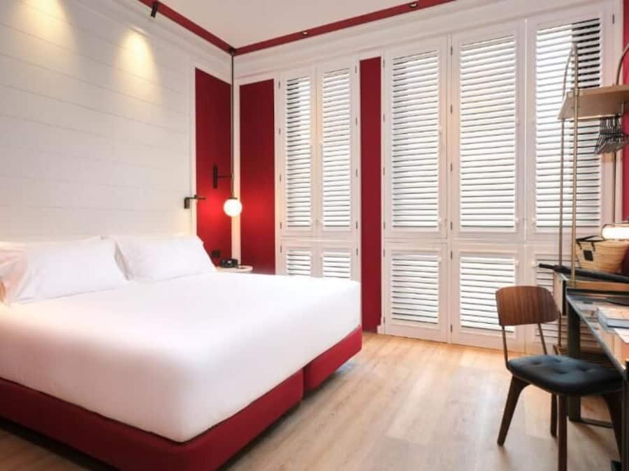 A bedroom with a bed, a desk, and a chair.