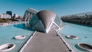 Una estructura arquitectónica moderna con un diseño único, que presenta una cúpula central y una estructura metálica circundante, ubicada en un entorno urbano bajo cielos despejados.