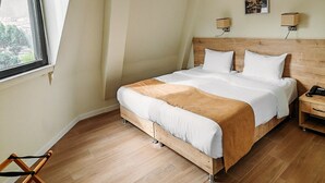 A modern hotel room with a large bed, wooden headboard, and a view of the city through the window. - Atrium Boutique Hotel (Tbilisi)