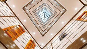 A modern atrium with a geometric ceiling design and a central skylight. - Atrium Boutique Hotel (Tbilisi)