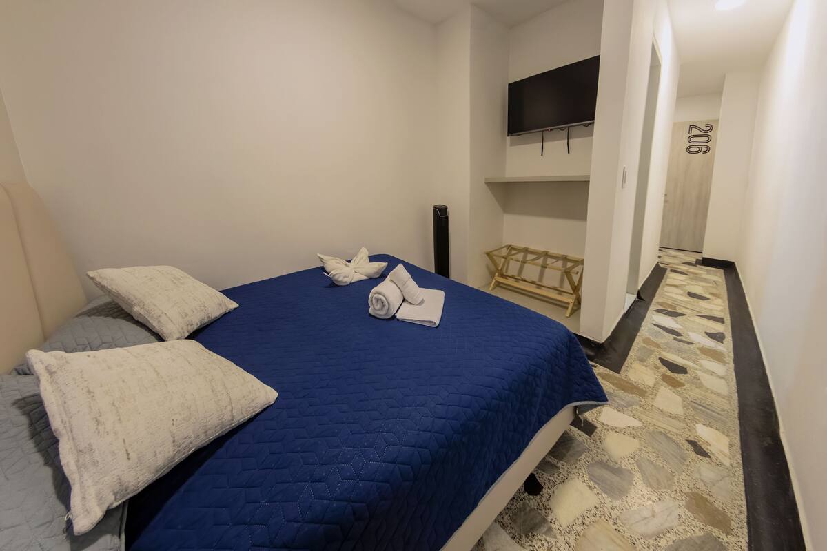 Una habitació d'hotel amb un llit ben fet, un televisor de pantalla plana fixat a la paret i un terrapat amb un disseny.