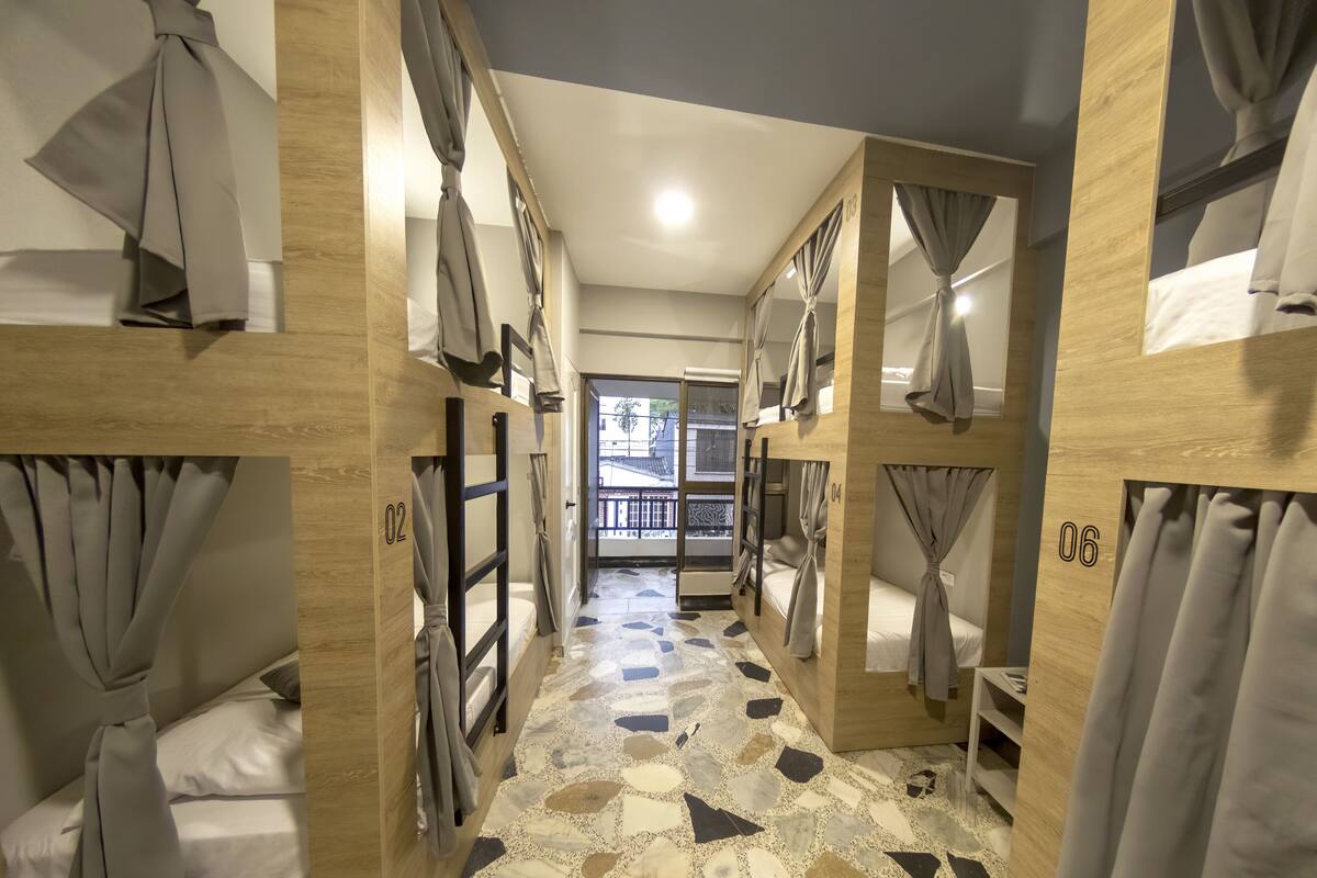 Passadís d'hotel amb lliteres, portes numerades i un paviment amb dibuixos.
