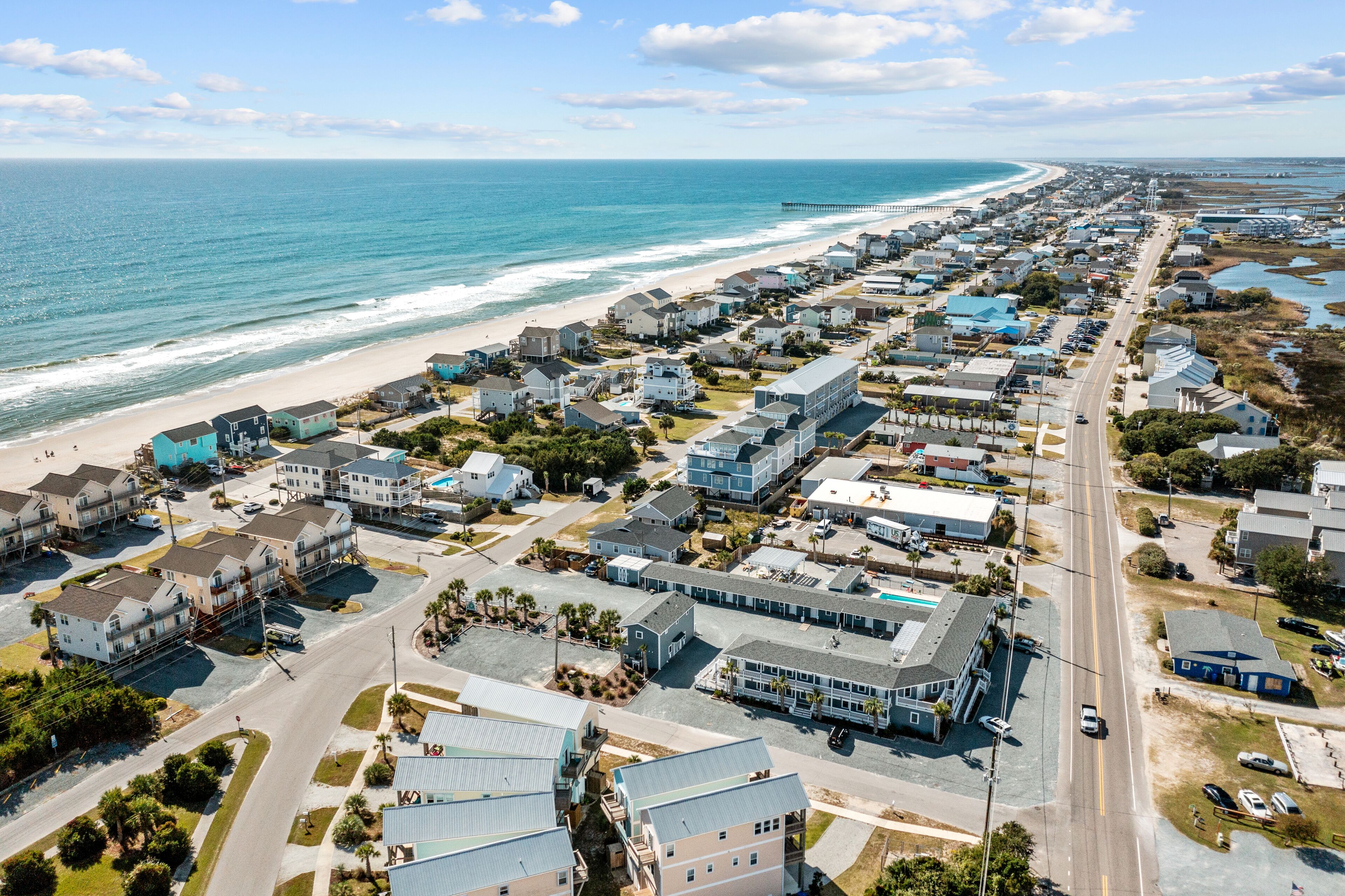 A coastal town with a beach, houses, and a pier.