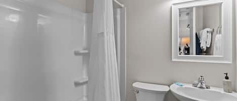 A bathroom with a shower curtain, a toilet, a sink, and a mirror.