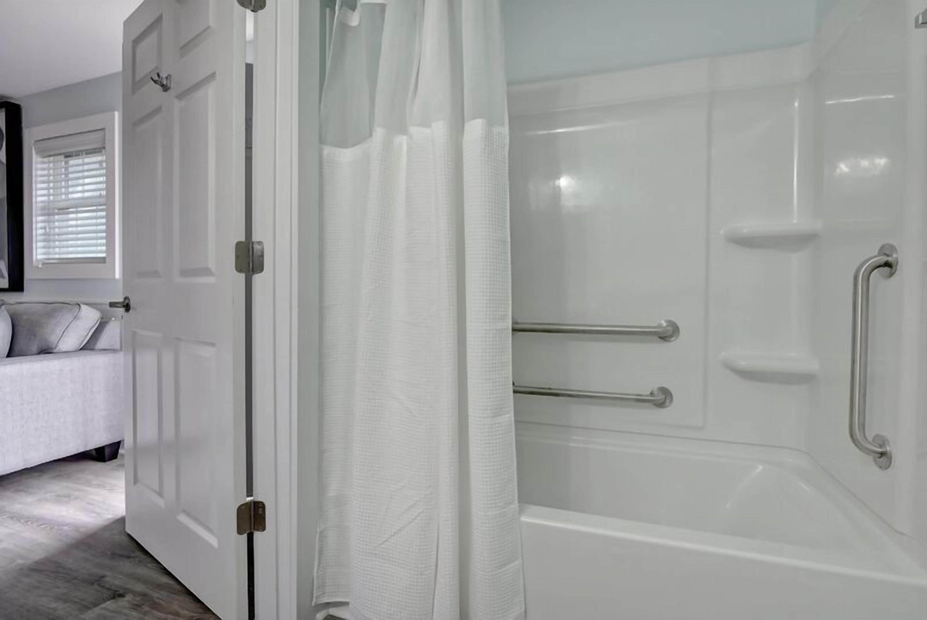A bathroom with a bathtub, a shower with glass doors, and a white door.